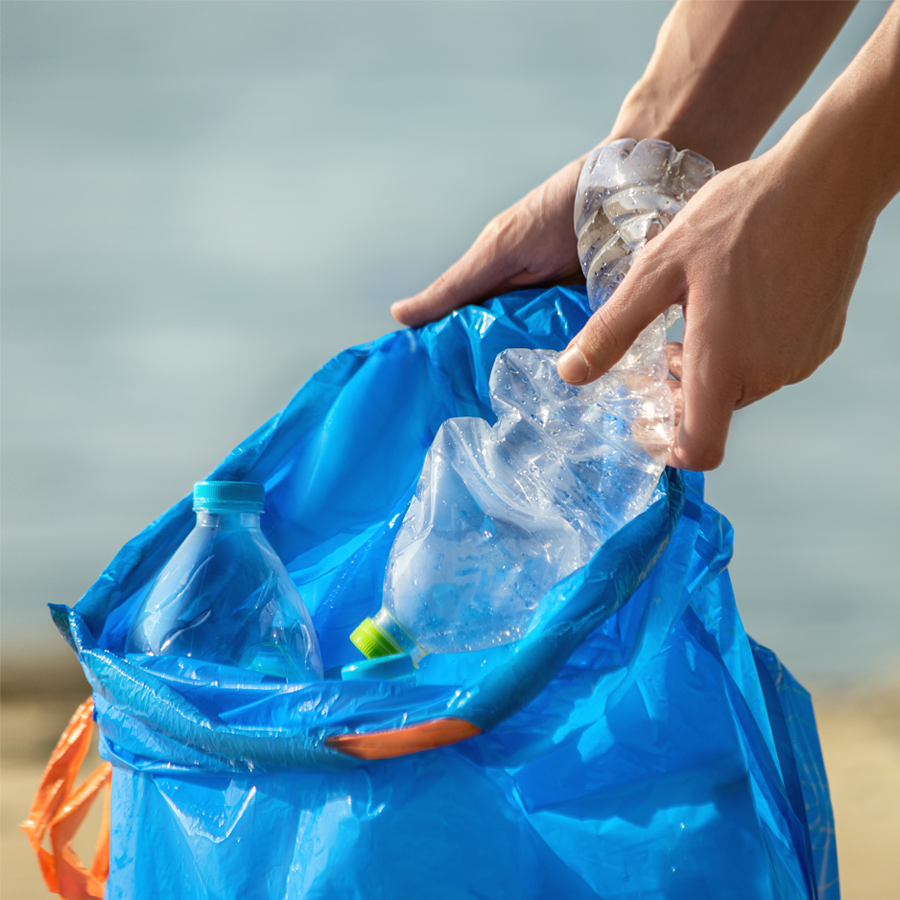 A person picking up plastic bottle and plastic trash from the beach to emphasise eco-friendly commitment
